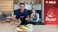 Philipp Jelinek und Tanja präsentieren in einer modernen Showküche die fertig zubereiteten Skyr-Bagels mit Liptauer-Aufstrich. Während Philipp motiviert beide Daumen nach oben zeigt, probiert Tanja einen der Bagels. Im Vordergrund ist ein Teller mit den goldbraun gebackenen Bagels und einer Schüssel des Aufstrichs ansprechend angerichtet.
